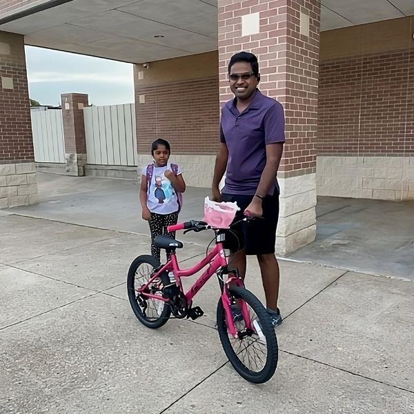 Child and parent in front of school with bicycles.